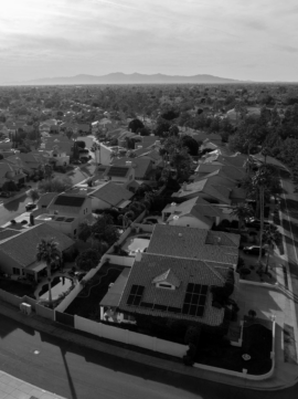 Aerial shot of a suburban neighborhood with houses, streets, and greenery.