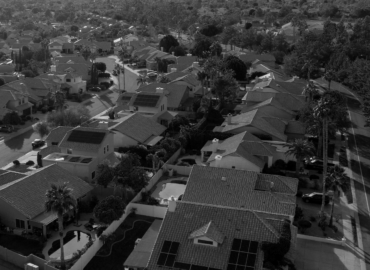 Aerial shot of a suburban neighborhood with houses, streets, and greenery.