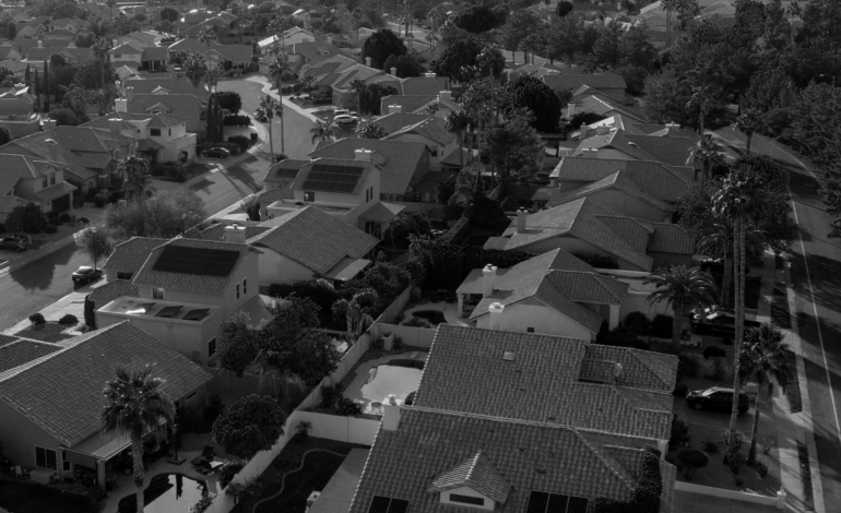 Aerial shot of a suburban neighborhood with houses, streets, and greenery.