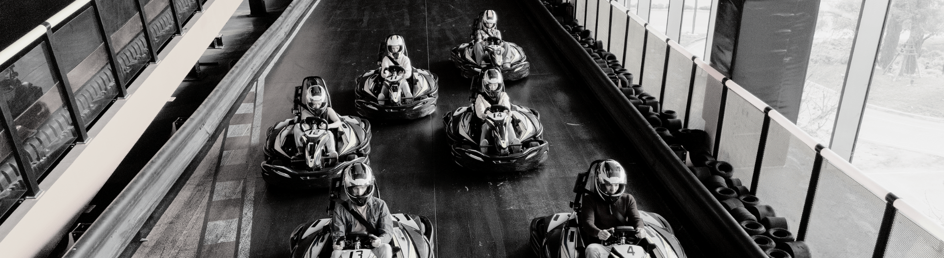 Go-karts racing inside a bright, window-lined track.