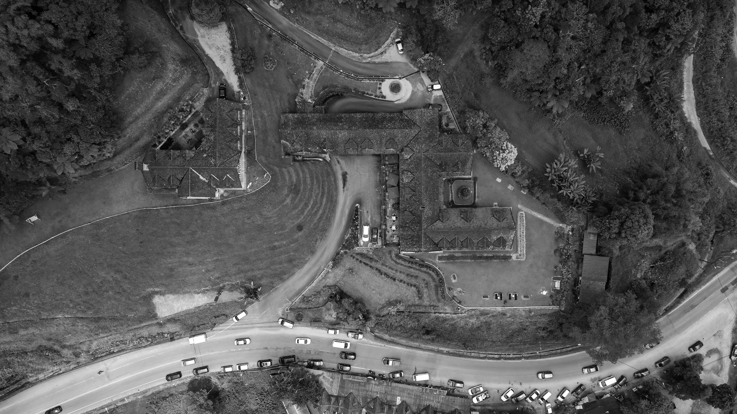 Aerial view of old houses nestled near a road surrounded by trees.