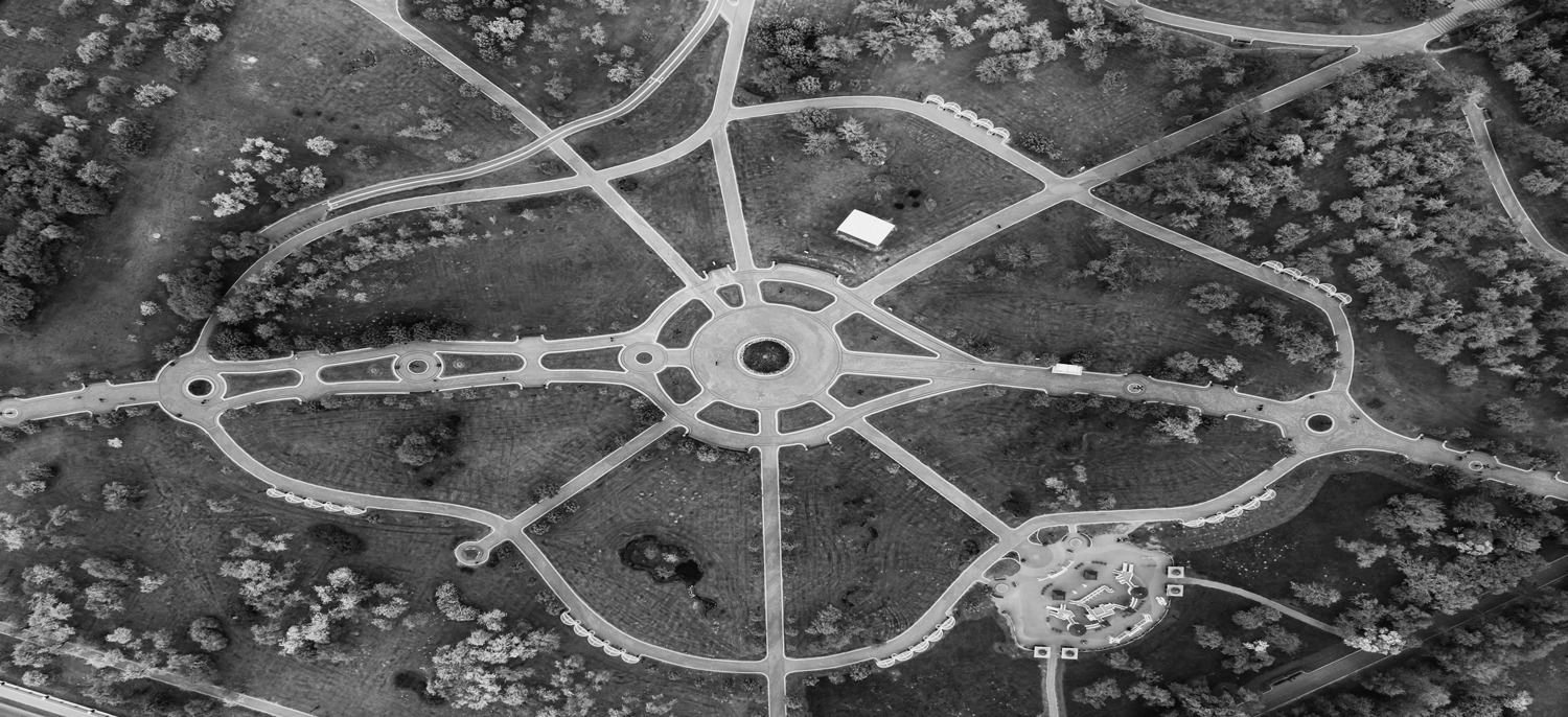 Aerial view of a lush green park with winding pathways and scattered trees.